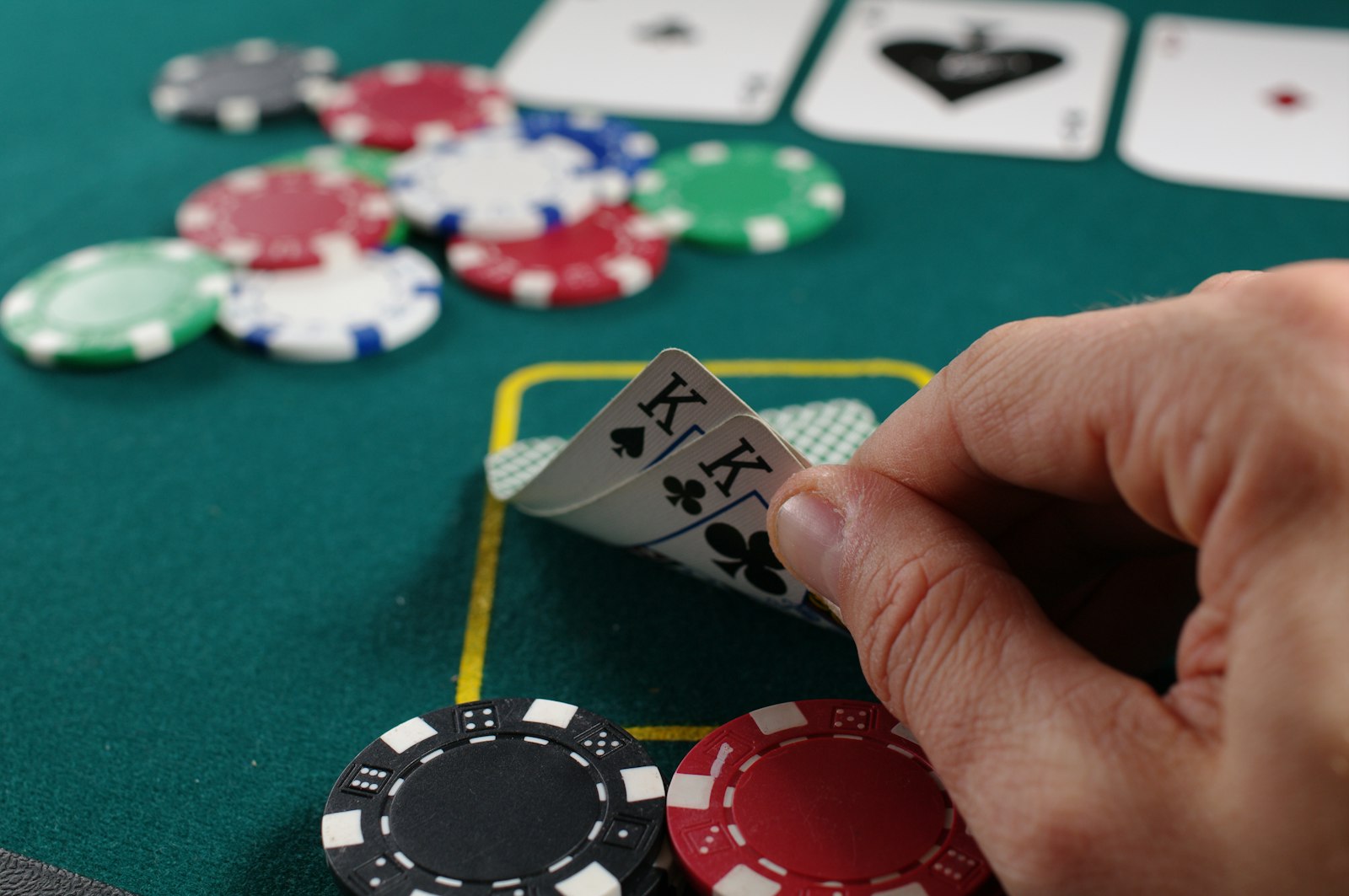 A player holding playing cards close at a poker table